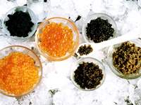 various black, coral and olive caviars in glass bowls on ice