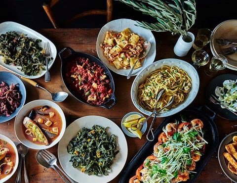 a variety of holiday seafood and non-seafood dishes served family-style on a wooden table